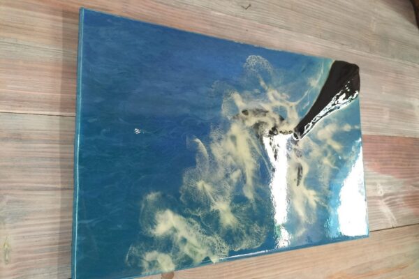 Cuadro rectangular de tonos azules, destaca la cola en relieve de una ballena